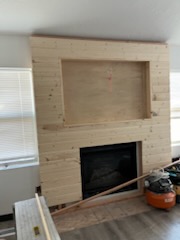 Fireplace surround part-clad in light timber board
