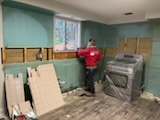 Kitchen mid-strip-out with backer board stacked against the wall