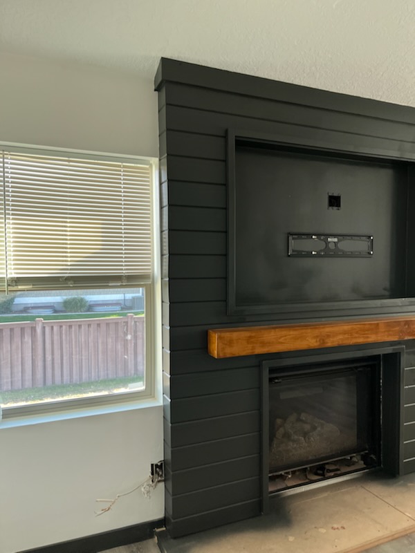 Dark shiplap fireplace surround with a timber mantel