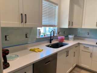 Glass tile backsplash above a light stone counter