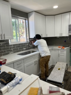 Worker at the sink in a kitchen with a tiled wall behind