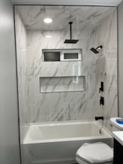 Tiled tub and shower surround with a recessed niche and a marble-look finish