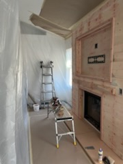 Room sheeted in plastic with a fireplace being clad in light timber
