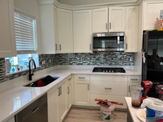 Mosaic tile backsplash behind a sink and cooktop
