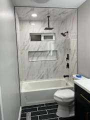 Finished tub and shower surround above a dark tile floor