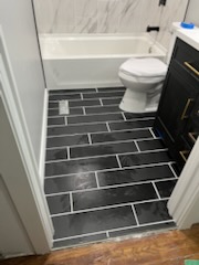 Bathroom with a dark tile floor, toilet and tub