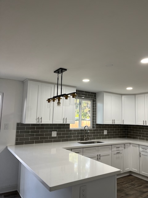 Finished kitchen with pendant lights above a tiled wall
