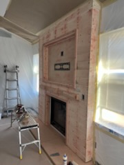 Fireplace surround being clad, with a ladder still in the room