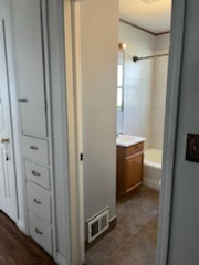 Hallway looking into a bathroom past a linen cabinet