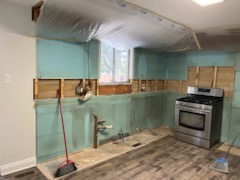 Kitchen mid-job with green board up and a band of wall cut open